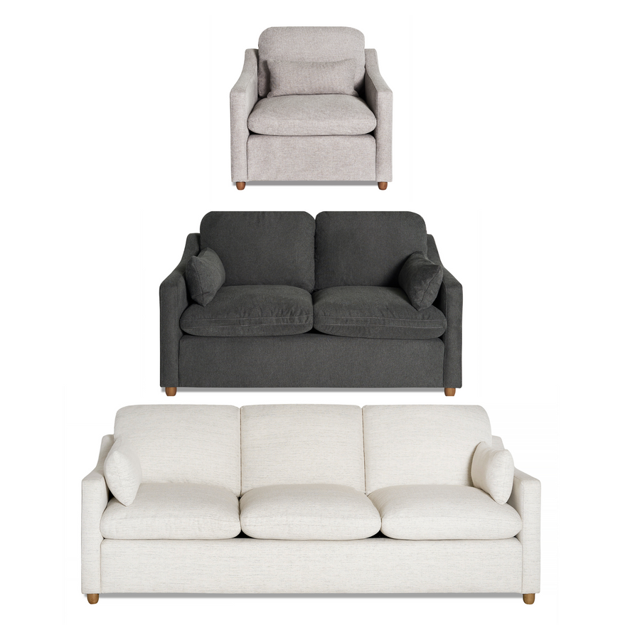 A cream-colored, modern sofa with three cushions and two armrest pillows. The sofa has a minimalist design with short wooden legs and a cozy fabric texture. Set against a plain white background.
