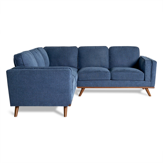 The Maddox is a modern, mid-century blue fabric sectional sofa with cushions and wooden legs. Its right-angle design provides contemporary and spacious living room seating against a white background.