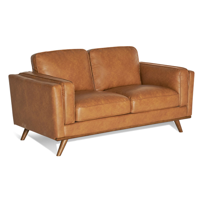 The Maddox Loveseat, a mid-century modern piece with angled armrests, plush cushions, and tapered wooden legs, sits elegantly on a white background.