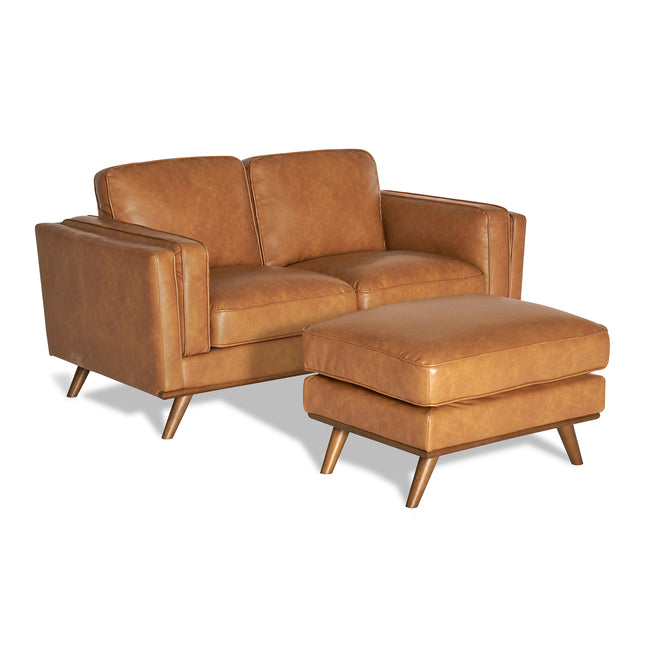 The Maddox Loveseat is a mid-century modern brown leather piece with plush cushions, paired with a matching ottoman and wooden legs, set against a white background.