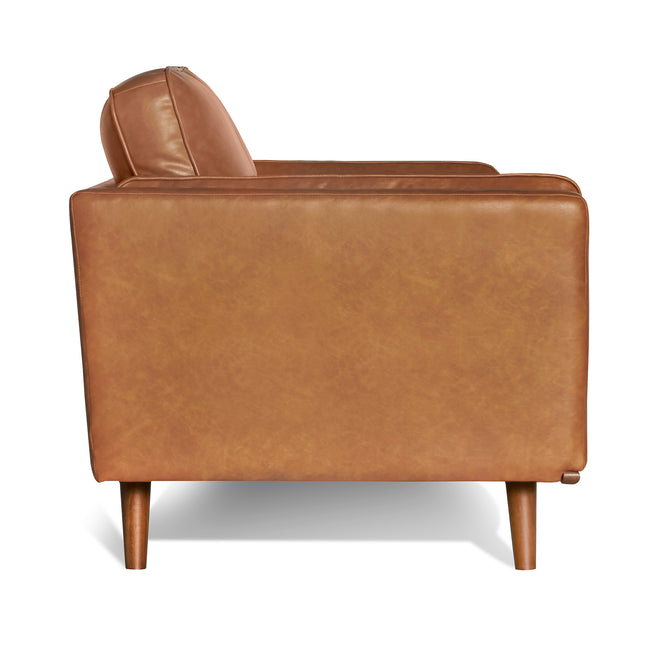 Tan leather armchair with wooden legs from the Maddox Sofa, showcasing a boxy design, smooth lines, and plush cushions for comfort with its subtle natural texture.