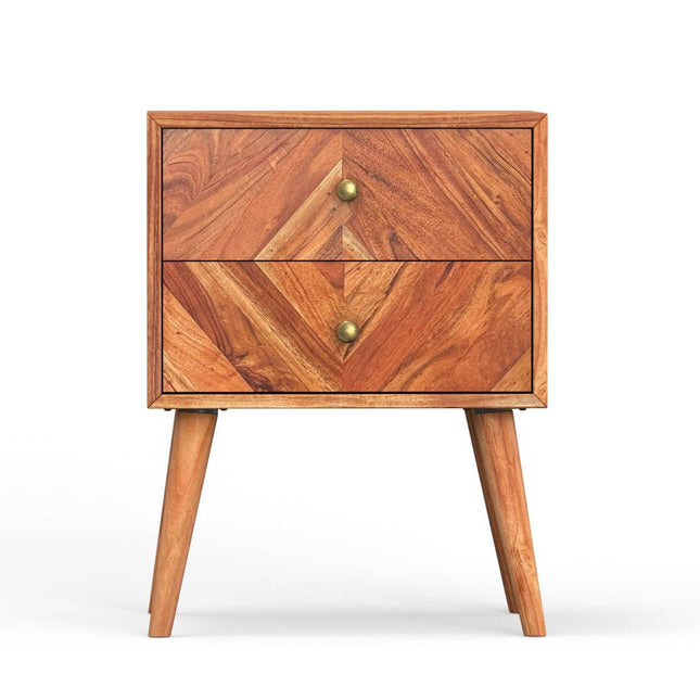 The MCM Bedside Table is a mid-century nightstand made from solid mango wood, boasting a herringbone pattern on its two front drawers. It stands on four tapered legs with brass knobs accentuating each drawer against a pristine white background.