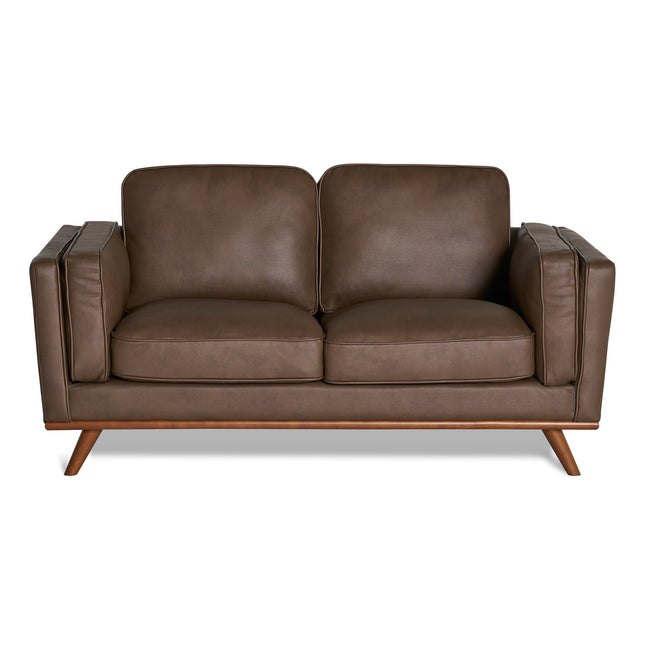 The Maddox Loveseat is a brown leather piece with plush cushions, two seat and back cushions, wide armrests, and angled wooden legs, embodying a mid-century modern aesthetic.
