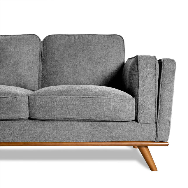 The Maddox is a modern gray sofa with two cushions and a wooden base, perfect for the living room. It boasts angled legs and clean lines for a mid-century modern aesthetic. The image shows the left half of the sofa against a white background.