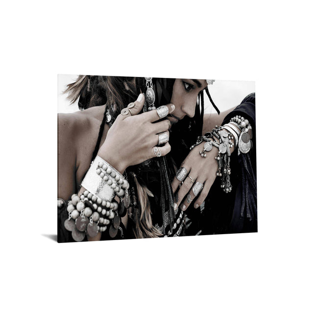 Adorned with Boho Jewels intricate silver rings, bracelets, and necklaces, a woman creates a lasting impression. Her heavily accessorized hands and arms complement her downward gaze. The image exudes a serene, artistic vibe akin to museum-quality artwork with its muted tones.