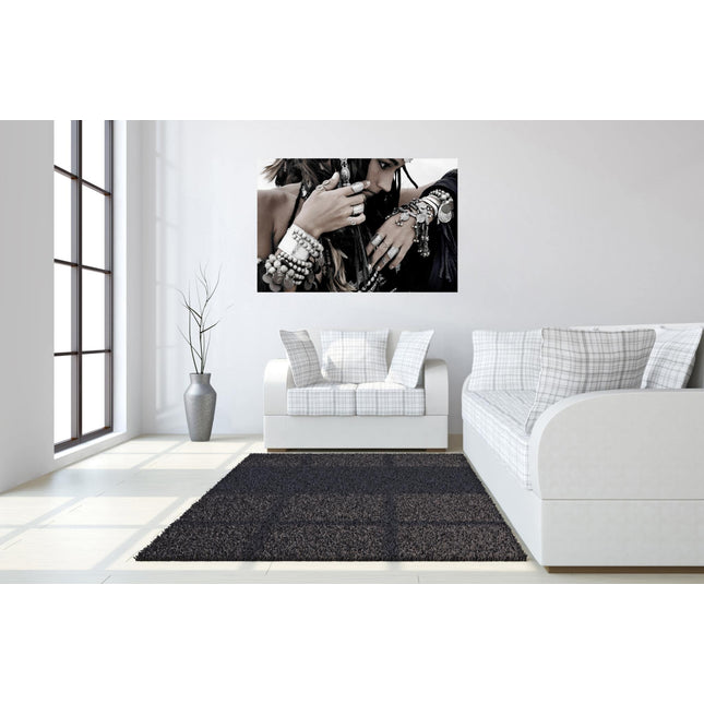 Modern living room featuring a white sofa and loveseat with plaid cushions. A large, museum-quality Boho Jewels photograph hangs above the loveseat. Nearby, a tall plant in a gray vase stands by the window, while a dark rug highlights the light floor.