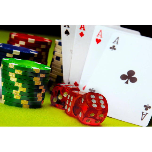 Stacks of green, black, and blue poker chips from the Vegas Baby set sit on a tempered glass table beside red dice. Behind them are four cards showing three aces: spades, hearts, and clubs—suggesting a winning hand.
