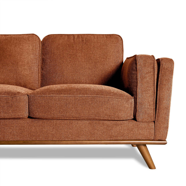 Close-up of Maddox, a mid-century modern sectional sofas right side in a cozy living room, showcasing orange-brown fabric upholstery and angled wooden legs. The sofa features two sections with cushioned seating and backrest.