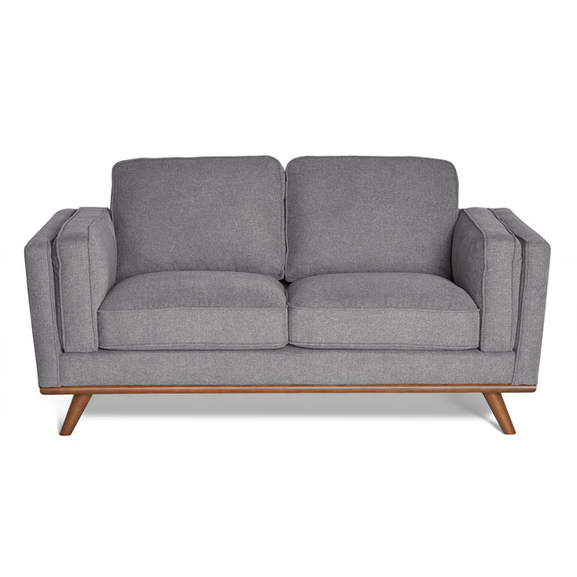 The Maddox Loveseat is a modern grey piece with plush cushions, armrests, a wooden base, and angled legs. Its smooth fabric texture and minimalist design make it perfect for mid-century modern interiors.