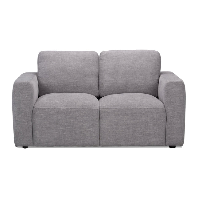 The Lugano Loveseat, part of the Lugano Sofa Set, is a modern gray piece with a minimalist design. It features plush back and seat cushions with wide armrests. Its textured fabric adds softness and style, perfect for contemporary or casual living spaces.