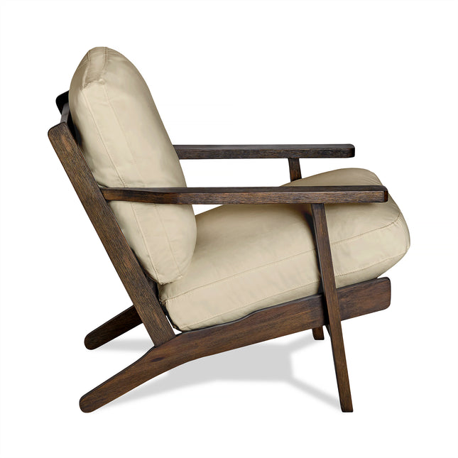 Side view of the Peyton Chair highlighting its mid-century design with a dark-finished wooden frame, complemented by angled legs and armrests. It features comfortable beige cushions on both the seat and backrest.