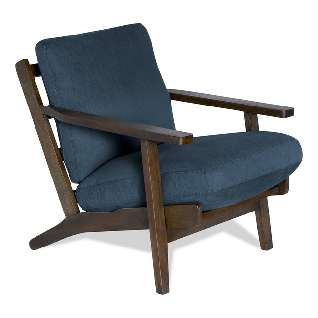 The Peyton Chair is a stylish, modern mid-century armchair with a dark wooden frame and deep blue cushions. It has angled legs and armrests for both comfort and a contemporary look.