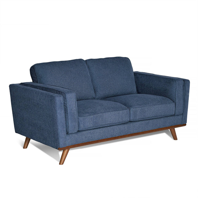 The Maddox Loveseat, a blue mid-century modern piece with a wooden base and angled legs, features plush fabric texture, large seat and back cushions, and wide armrests for an inviting appeal.