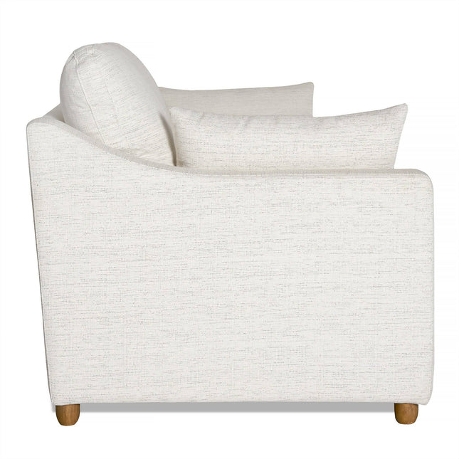 Side view of the My Cloud Slope Sofa in white, featuring clean lines, light wood legs, cushioned armrests and back, plus an extra throw pillow. Set elegantly against a white background.
