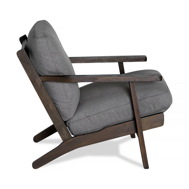 Side view of the Peyton Chair, featuring gray cushions and a dark wooden frame. This cozy armchair has a mid-century style with angled legs and armrests, ideal for contemporary living spaces.