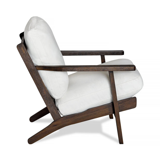 The Peyton Chair is a modern lounge masterpiece featuring a mid-century style with a dark wooden frame and angled legs that complement its white cushioned back and seat for a sleek, comfortable look.