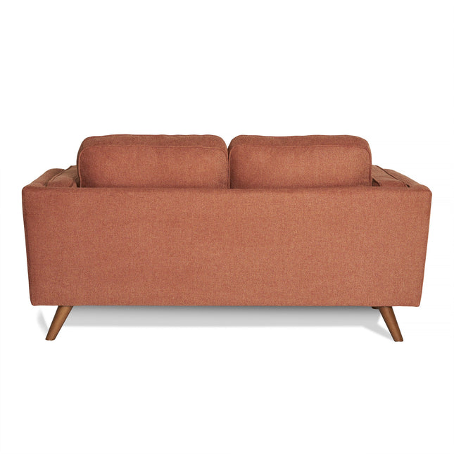 The Maddox Loveseat showcases a back view with rust-colored upholstery, wooden legs, and two plush back cushions. Its design features a simple rectangular shape in mid-century modern style.